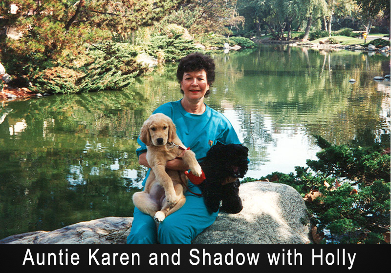 Woman with her two dog sitting on a rock with a pond behind her